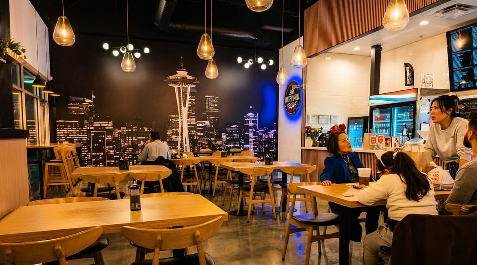 Restaurant interior with a Seattle skyline mural, wooden tables, and people dining.